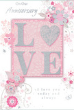 This anniversary card is presented as though resting on a calm Pimlico coffee table, radiating a gentle celebration of enduring love through its soft pastel design. The central focus is the word LOVE, crafted in raised, velvety glitter that feels smooth yet delicately textured under the fingertips. The letter O is playfully transformed into a shimmering silver heart, embossed so that it catches the light like a tiny keepsake locket, adding warmth and intimacy to the overall composition. Surrounding this central motif, a halo of blush and mauve flowers unfurls with a dreamy, watercolour softness, their edges feathered and slightly translucent as though washed gently by a fine brush. Slender stems and swirling vines snake gracefully across the card, punctuated by small petals, curls, and near-hidden butterflies that give a sense of movement, as if a soft breeze from the Thames has just ruffled a bouquet delivered to a home off Belgrave Road. The colour palette-dusty pinks, silvery greys, and hints of pearl-creates a refined, romantic atmosphere reminiscent of a bespoke anniversary arrangement prepared by Florist Pimlico for a couple marking years together. Elegant, flowing script spells out On Our Anniversary and I love you today and always, the letters slightly raised and gently inked, adding both visual and tactile interest. Together, these details form a tender, keepsake-quality card that feels like a whispered promise, ideal for marking a shared journey of love and loyalty in the quiet charm of Pimlico.